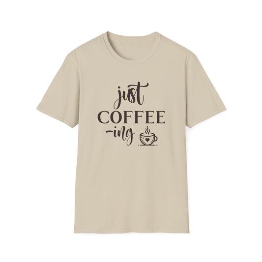 Sand t-shirt with ’Just Coffee -ing’ text and a freshly made coffee on a mug with a heart design on a sand color background